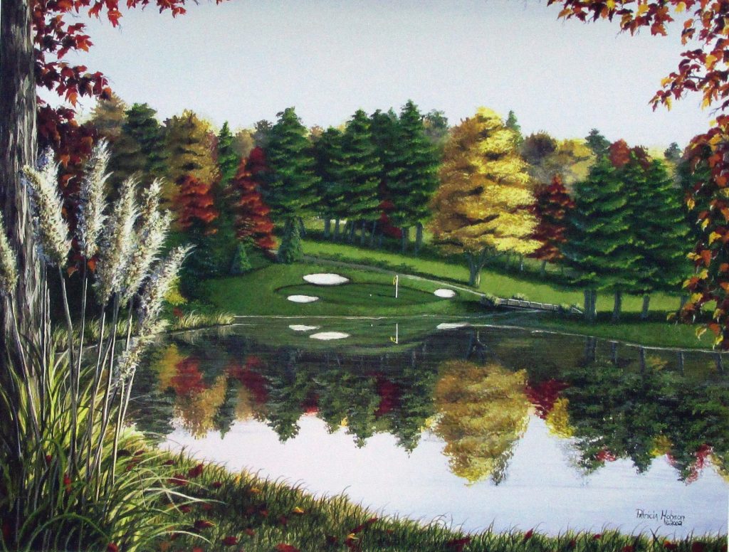 This fall art print features the 17th hole at the Yadkin Country Club in Yadkinville, North Carolina. The green lies across the lake on a slope. The the golf green and fall leaves of the trees are reflected in the lake.