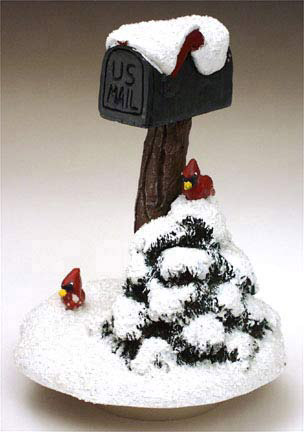 A small sculpture featuring a mailbox in the snow with a pair of cardinals.